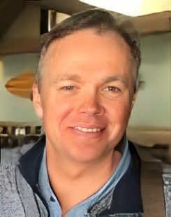 Smiling man indoors, wearing casual clothing.