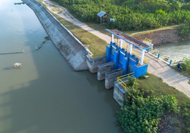 Blue water control structure near riverbank.