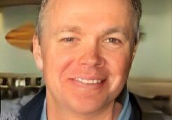 Smiling man indoors, wearing casual clothing.